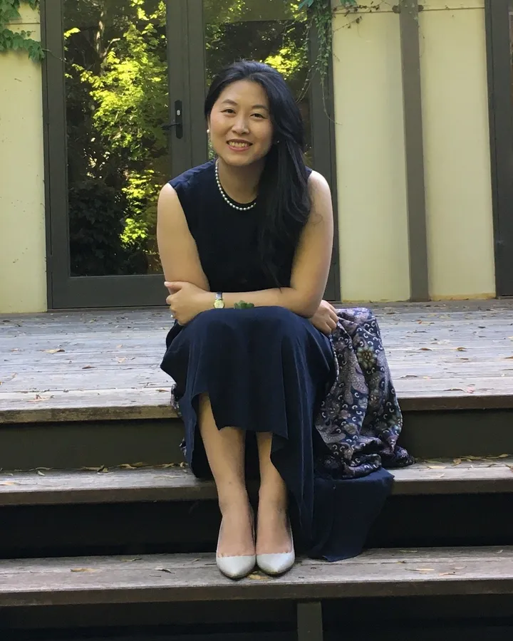 Chun Yin, founder of Base Camp, seated on timber steps outside an ivy-covered building